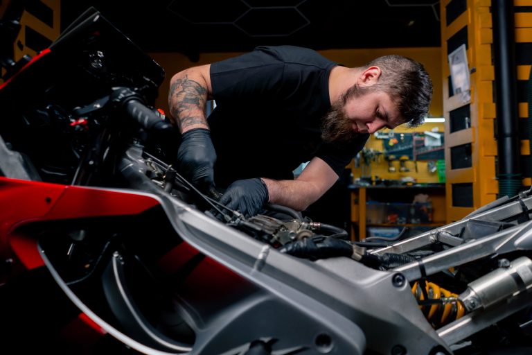 At a motorbike repair shop a master unscrews the core of a motorbike with a screwdriver