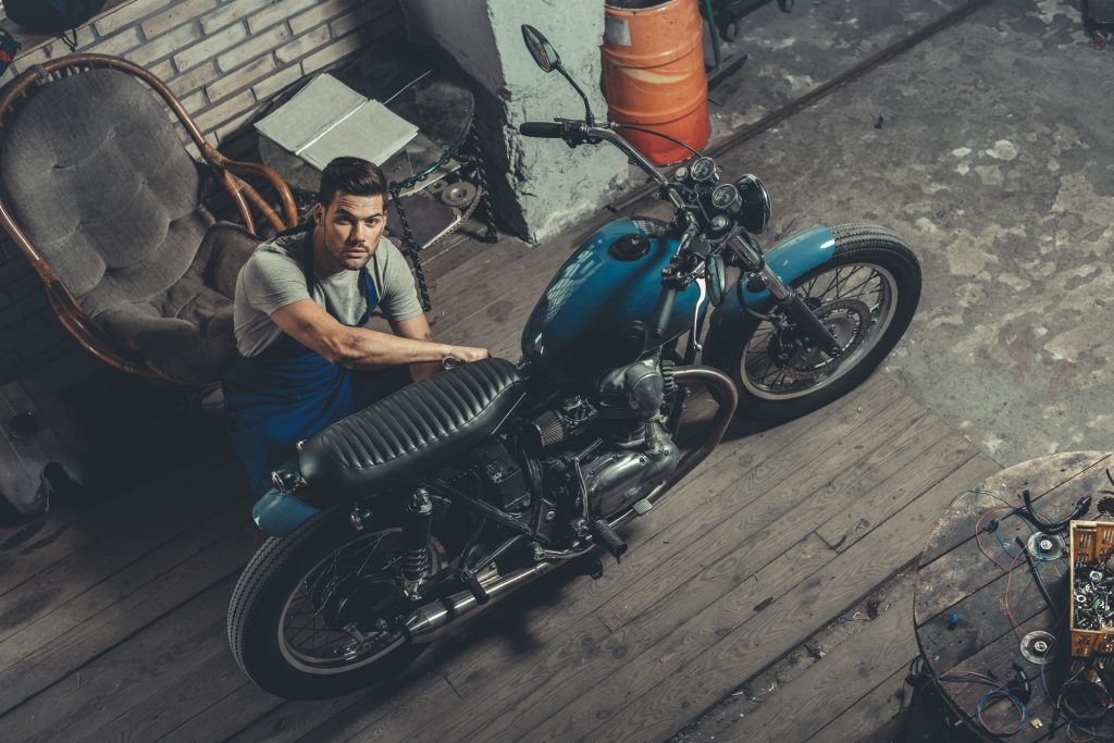 handsome mechanic working in repair shop with motorbike
